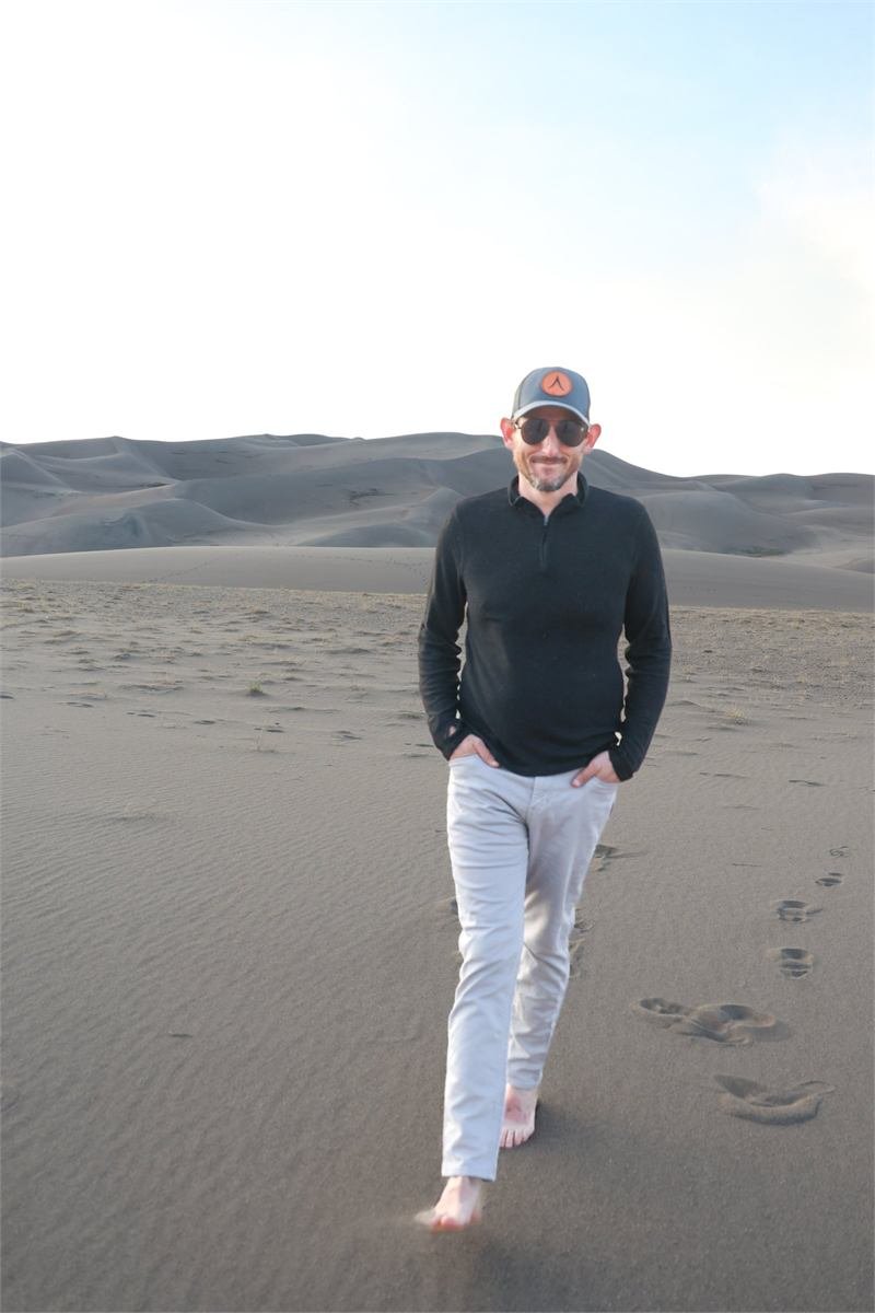 Evan Lightner walking across sand dunes